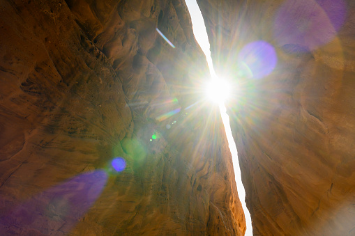 Low angle view with dramatic lens flare of natural narrow passageway through mountain, providing access to Jabal Ithlib.
