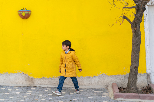 boy wandering the streets of the old neighborhood. colorful walls and cobblestone streets. deciduous tree planted on the sidewalk. Taken in daylight with a full frame camera.