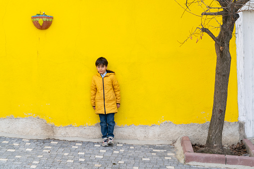 boy wandering the streets of the old neighborhood. colorful walls and cobblestone streets. deciduous tree planted on the sidewalk. Taken in daylight with a full frame camera.