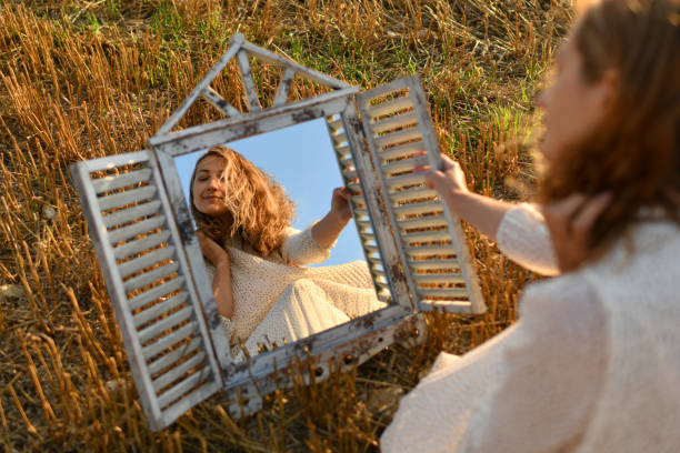 istock Woman looking into a mirror in a wheat field 2005859113
