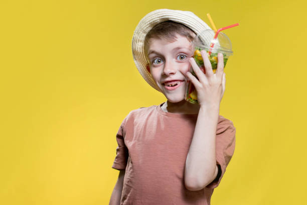 Cute little boy with inflatable ring and  glass on yellow background