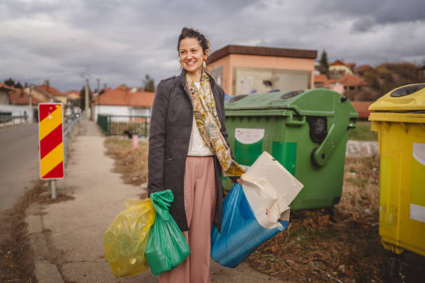 istock one woman stand with sorted garbage in front of recycle containers 2005881882