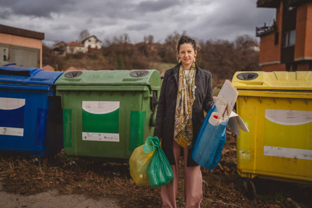 istock one woman stand with sorted garbage in front of recycle containers 2005884034