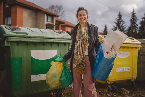 istock one woman stand with sorted garbage in front of recycle containers 2005885647