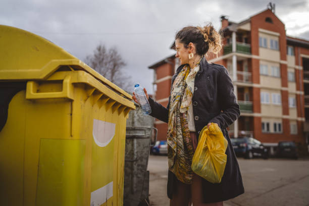 istock one woman stand with plastic garbage in front of recycle containers 2005894660