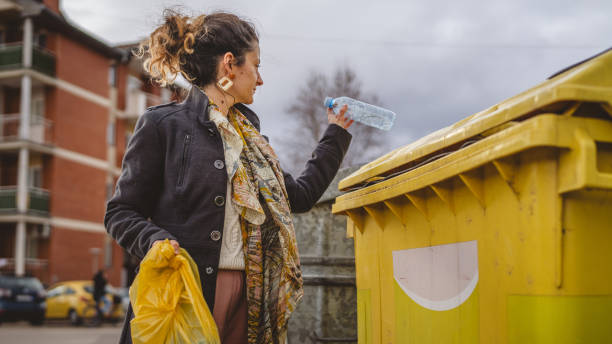 istock one woman stand with plastic garbage in front of recycle containers 2005896822