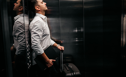 Young businessman in an elevator getting ready to check out in a hotel