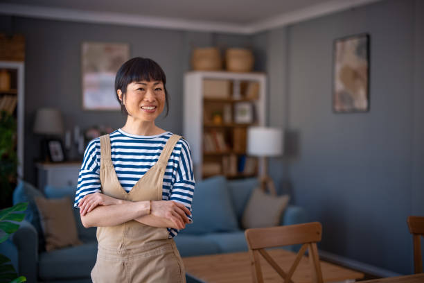 istock Happy smiling asian mid woman relaxing at home 2005912321