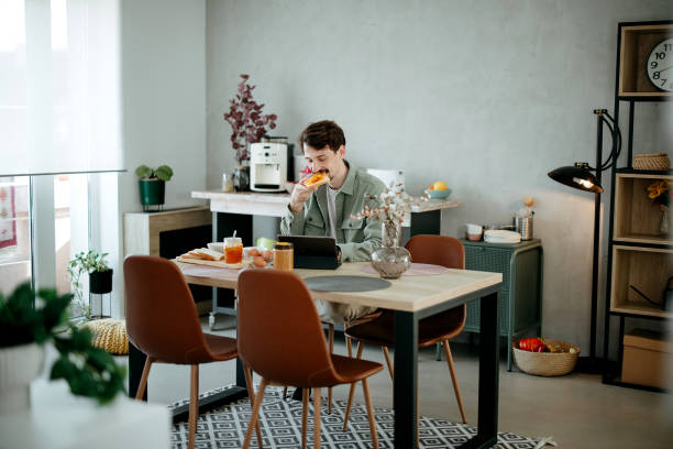 istock man has breakfast in the dining room and uses a tablet​ 2005914499