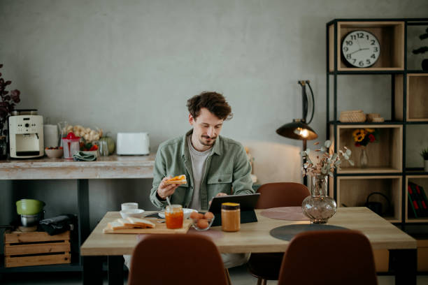 istock man has breakfast in the dining room and uses a tablet​ 2005914505