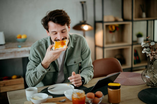 man has breakfast in the dining room and uses a tablet
​