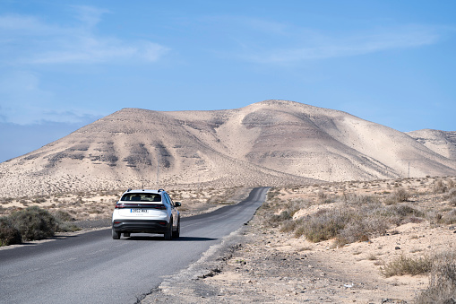 A white colored Volkswagen Taigo rental car passing by in Jandia on Fuerteventura, Canary Islands.