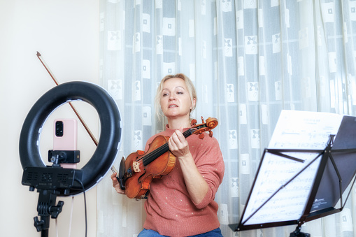 A music teacher teaches violin playing online