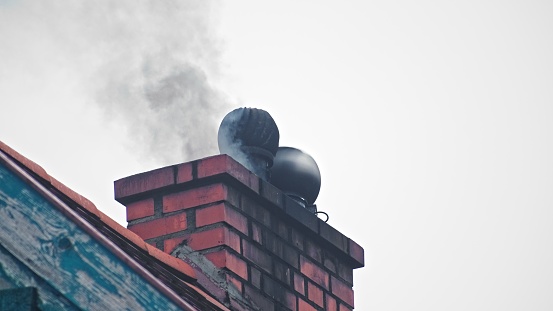 Black Toxic Smoke Floating out of House Chimney with Rotating Metal Ventilator Cap