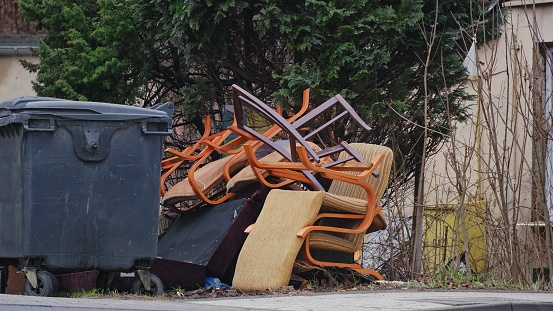 Old Furniture Stacked By Dumpster for Curbside Garbage Collection by City Cleaning Service