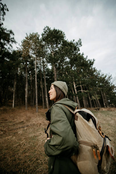 Woman with backpack hiking on footpath in forest