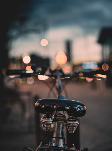 close-up of a bicycle saddle with blurred city light in the background. street photography. art concept