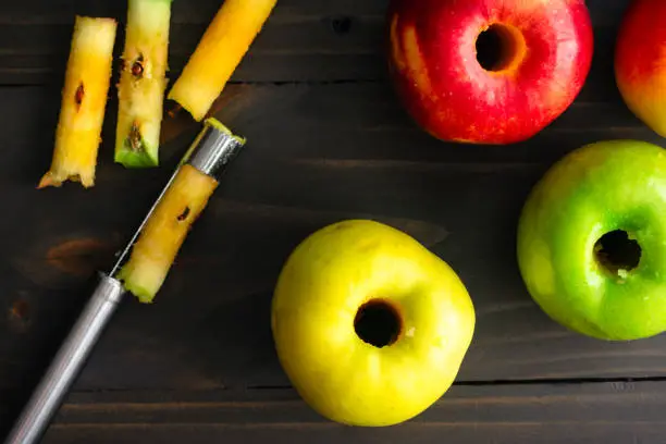 Ambrosia, Golden Delicious, and Granny Smith apples with a coring tool on a dark background