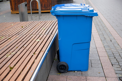 Blue garbage bin on the street. Public trash on the side of the road. Hygiene concept.