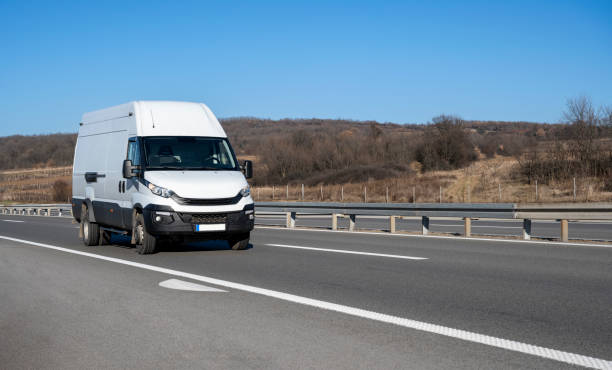 istock White modern delivery small shipment cargo courier van moving fast on motorway road to city urban suburb. 2006058272