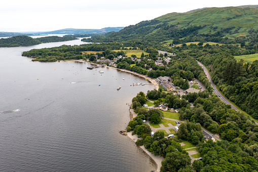 An aerial image of Luss, Scotland, showcasing this charming village set on the banks of Loch Lomond. Known for its quaint cottages, beautiful gardens, and scenic waterfront, Luss embodies the tranquil beauty of the Scottish countryside, making it a picturesque and peaceful destination.
