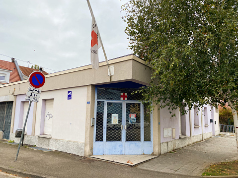 Strasbourg, France - Oct 2020: Large empty closed office of Croix Rouge Francaise French Red cross branch in poor neighborhood of Strasbourg - large flag and closed steel door