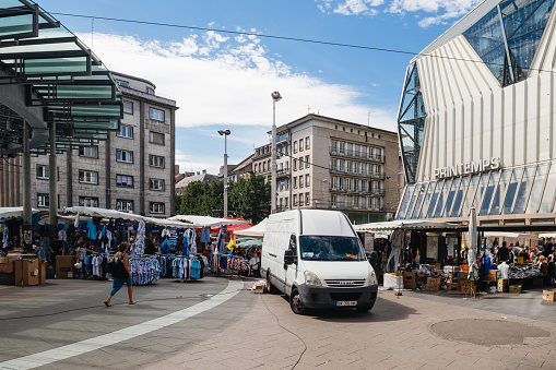 Strasbourg, France - July 29, 2017: Large crowd of people walking on the tramway station Homme de Fer and Printemps store during the Grande Braderie street fair annual sale event - Iveco van parked