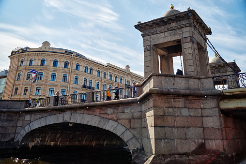 Saint-Petersburg, Russia - June 11, 2023: Below view of Lomonosov bridge across the Fontanka river and pedestrians in the historical center of St. Petersburg, Russia.