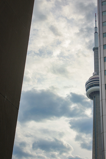 Toronto, Canada - September 2014: The famous CN Tower peeking out of a skyscraper from the corner of Front Street W and York Street, right by Union Station. Featuring beautiful skies after a cloudy and moody day.