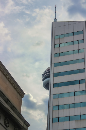 Toronto, Canada - September 2014: Close-up of the famous CN Tower peeking out of a skyscraper from the corner of Front Street W and York Street, right by Union Station. Featuring beautiful skies after a cloudy and moody day.