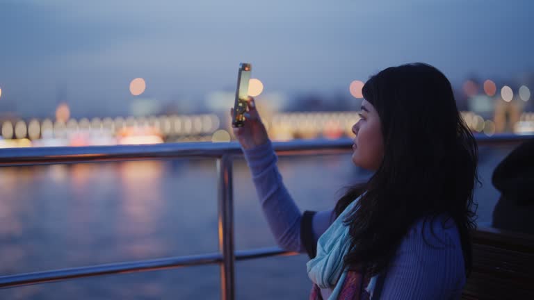 Multiracial female solo traveler taking photos and videos in Istanbul Türkiye Turkey at night