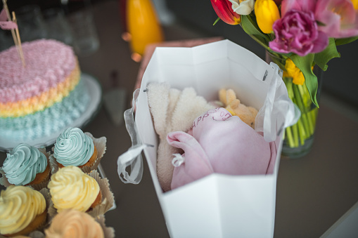 A beautifully curated baby shower celebration with a stunning pastel cake, delicate macarons, and gifts in a small bag.