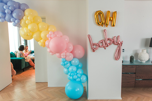 A baby shower table adorned with a multi-tiered rainbow balloons,  a contemporary space.