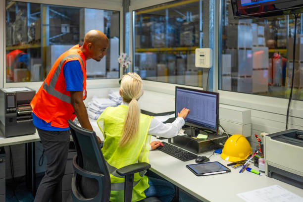 shipping operator showing orders list to worker - computer control room hardhat computer monitor 뉴스 사진 이미지