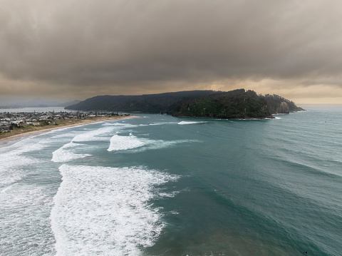 An aerial shot of Whangamata Beach at dawn on a stormy morning.