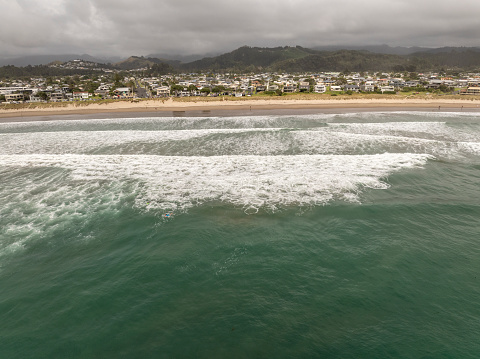 An aerial shot of Whangamata Beach at dawn on a stormy morning.