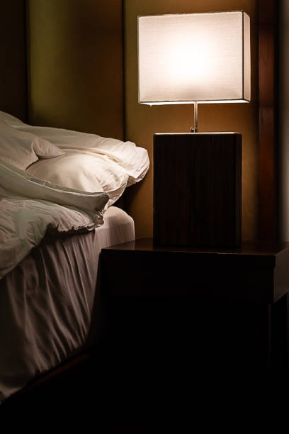 Bedside lamp turns on in bedroom at dusk.