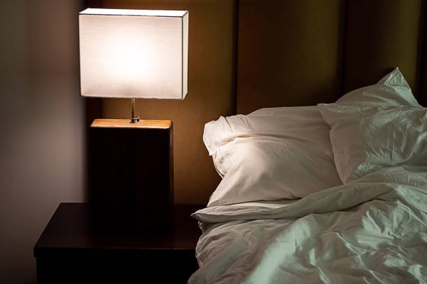 istock Bedside lamp turns on in bedroom at dusk. 2006572094