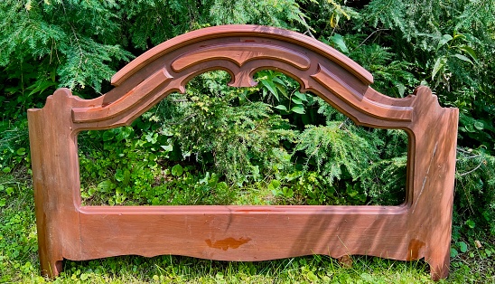 A beautiful mahogany wood footboard set on grass.