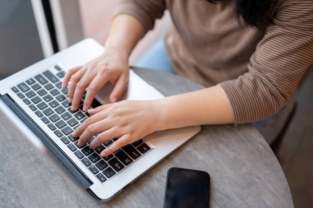istock A woman working on her laptop computer in a cafe, typing on the laptop keyboard, responding to email 2006641373