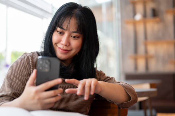 istock A positive Asian woman is reading texts on her smartphone while relaxing in a cafe. 2006647677