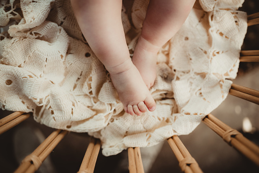 Chubby baby legs and toes in a rustic wicker bassinet