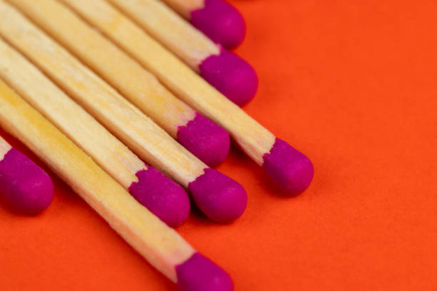 long wooden matches on a paper background, matches with a red pink substance for lighting on an orange background
