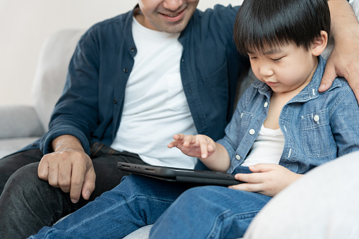 Happy single father playing teach using tablet with the little boy. family is happy and excited in the house. Father and son having spending time together, Good daddy , addiction fix, handle, control