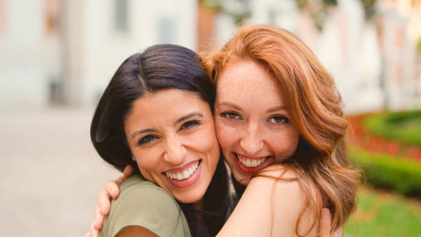 istock Best friends embracing while smiling in the street 2006857495