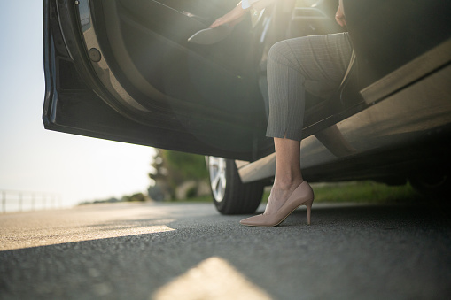 Low section shot of unrecognizable businesswoman getting out of car on the street