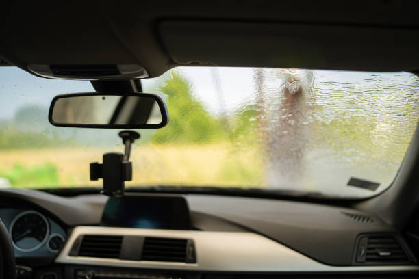 Mature woman washing car in self-service station,  view from inside of car