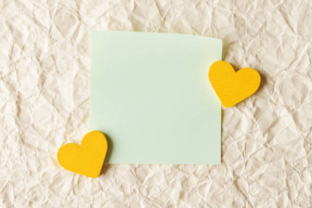 Green Note with Yellow Hearts on Textured Paper Background