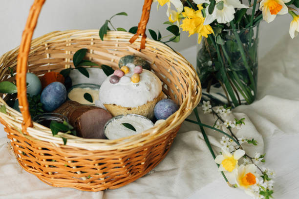 istock Happy Easter! Stylish easter basket with natural dyed eggs, meat, bread, butter, beets and spring flowers on rustic table. Traditional easter orthodox holiday food and daffodils bouquet 2006983777
