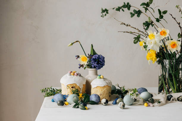 istock Happy Easter! Stylish easter eggs, homemade easter bread and spring flowers on linen napkin on rustic table. Natural painted marble eggs, daffodils bouquet and holiday food. Modern still life 2006985580